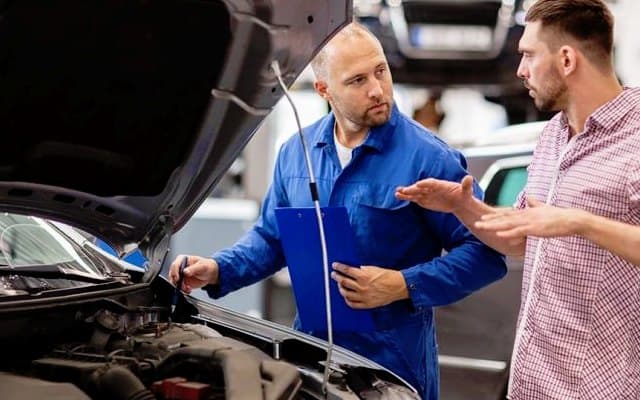Auto repair shop owner or service advisor speaking with a customer